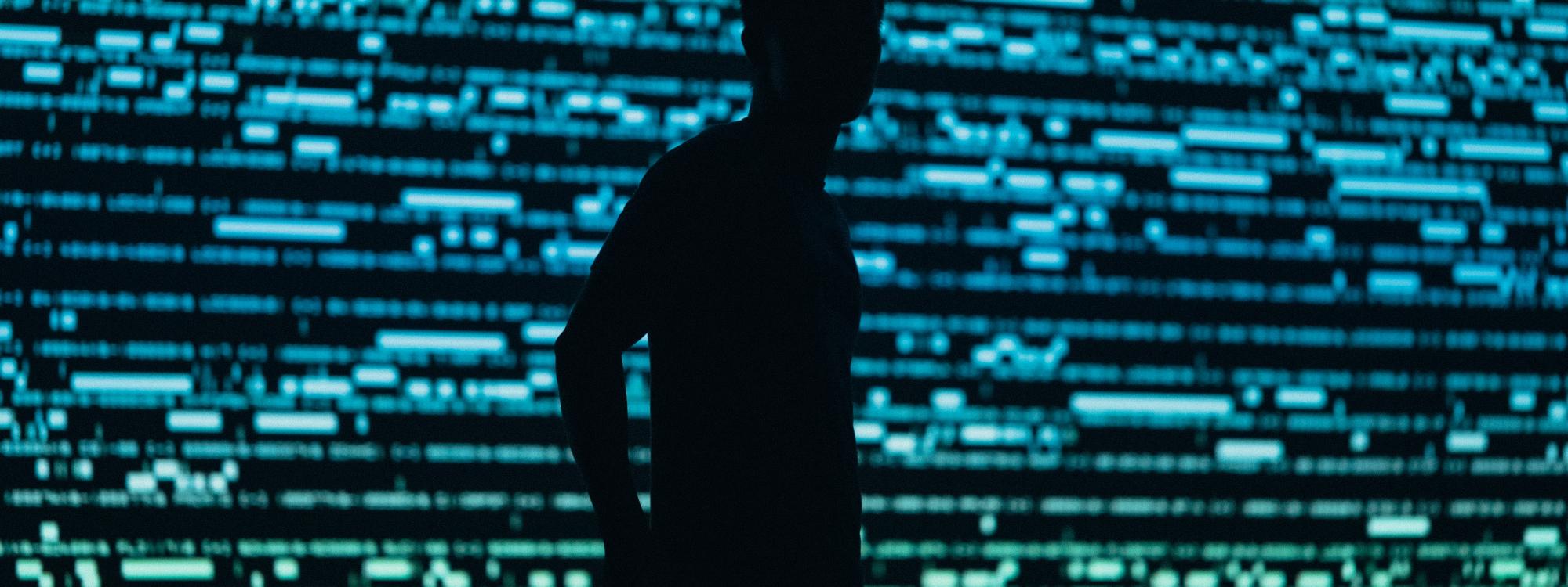 Shadow of man standing in front of computer text